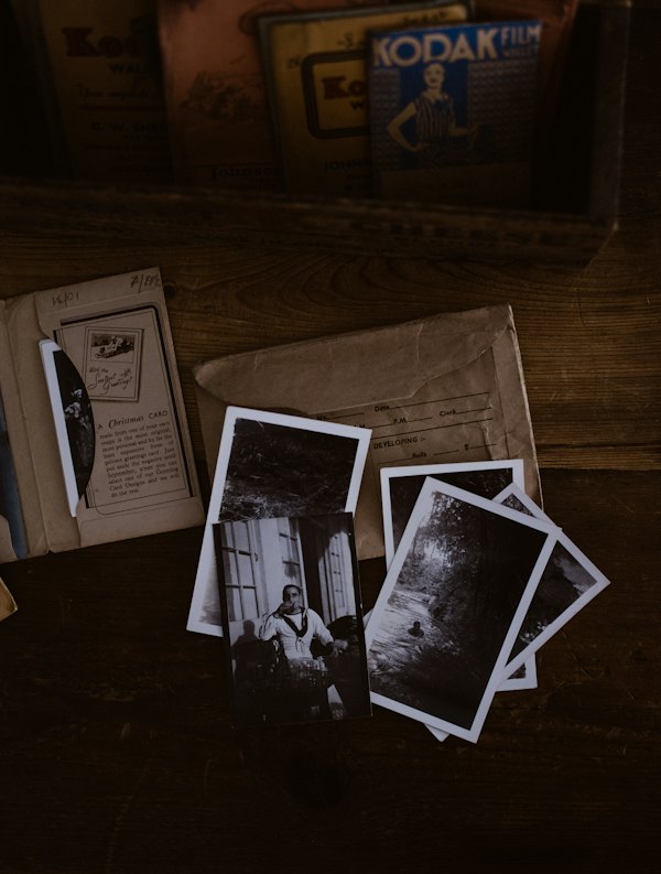 Old black-and-white photographs scattered on a dark wooden table.