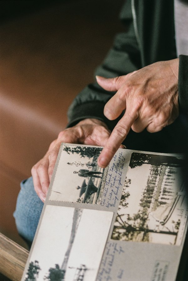 A finger points to a small old photograph held in someone’s hand.