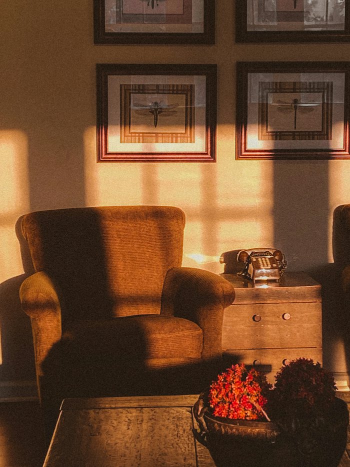 An armchair and side table in a room lit by warm evening sun.