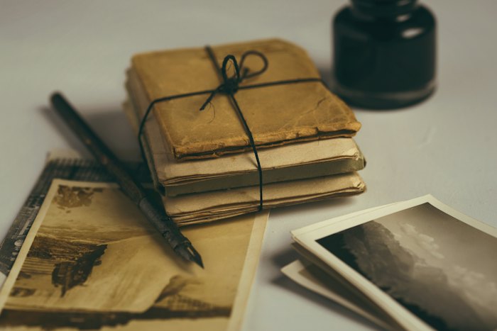A tied bundle of old letters, a fountain pen and photographs on a table.