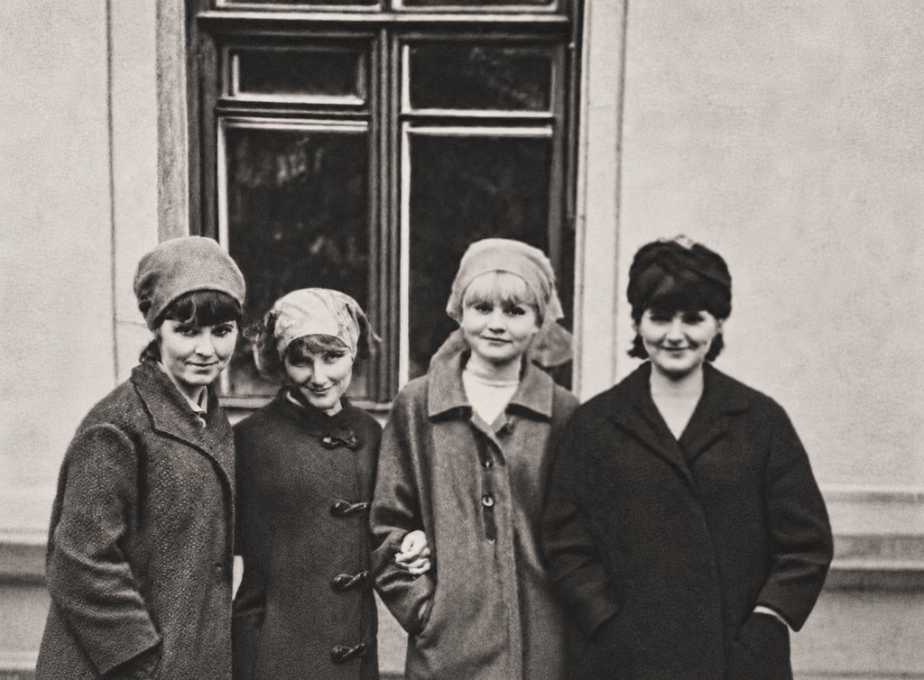 The same photograph after restoration: the stains and cracks are gone and the four women are sharp and evenly lit.